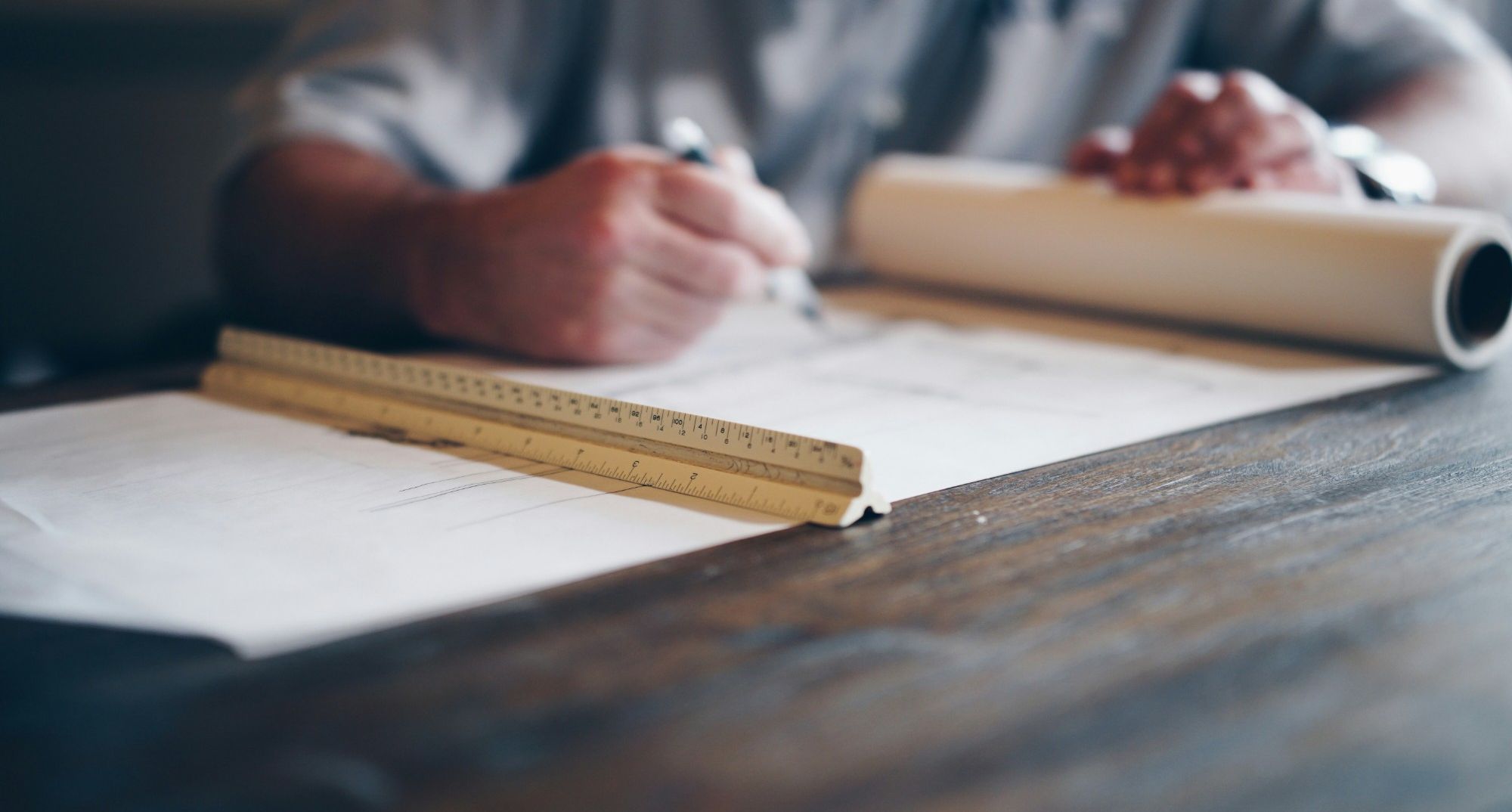 Architect drawing on a building plan with a scale ruler